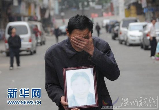 4月5日，在廣東省東莞市鳳崗鎮，肖國海捧著妻子吳喜英的遺像掩面哭泣。