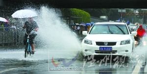 閃 潘家園橋下，汽車掀起的積水飛濺到騎自行車人的身上。本報記者 尹亞飛 攝
